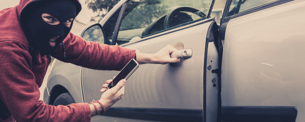 Criminal Accessing a Vehicle in a Parking Lot Showing a Need for Security Solutions