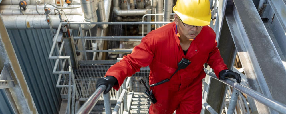 A lone worker - wearing a MOTOTRBO two-way radio - performing a routine check on a remote pipeline pumping station.