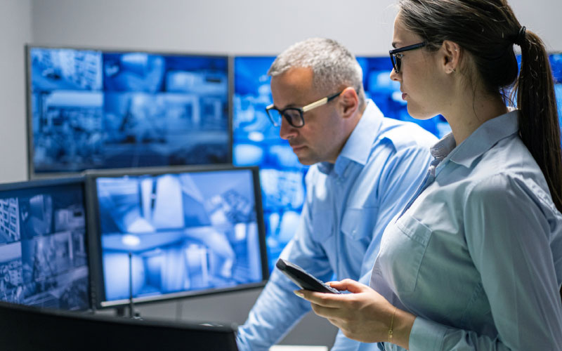 Two operators watch live feed from a video wall.