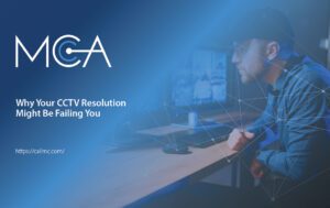 A surveillance worker leans in to decipher a figure on one of his multiple screens.