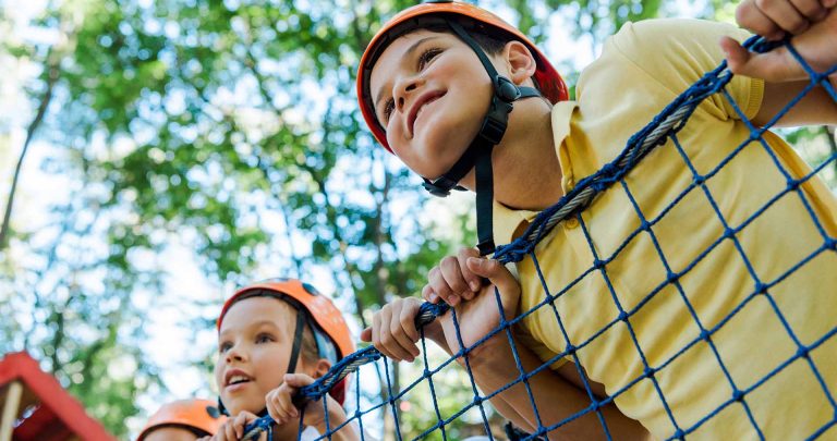Young kids - wearing safety gear - enjoying a ropes course.